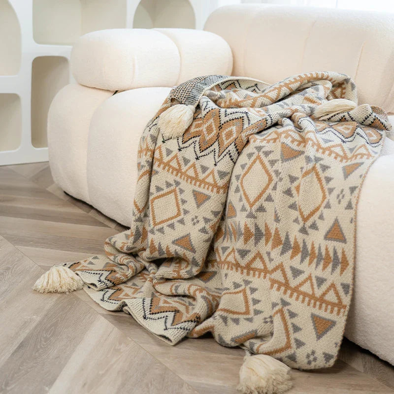 Gestrickte Quastenwurfdecke mit neutralem Streifenmuster und Boho-Akzenten